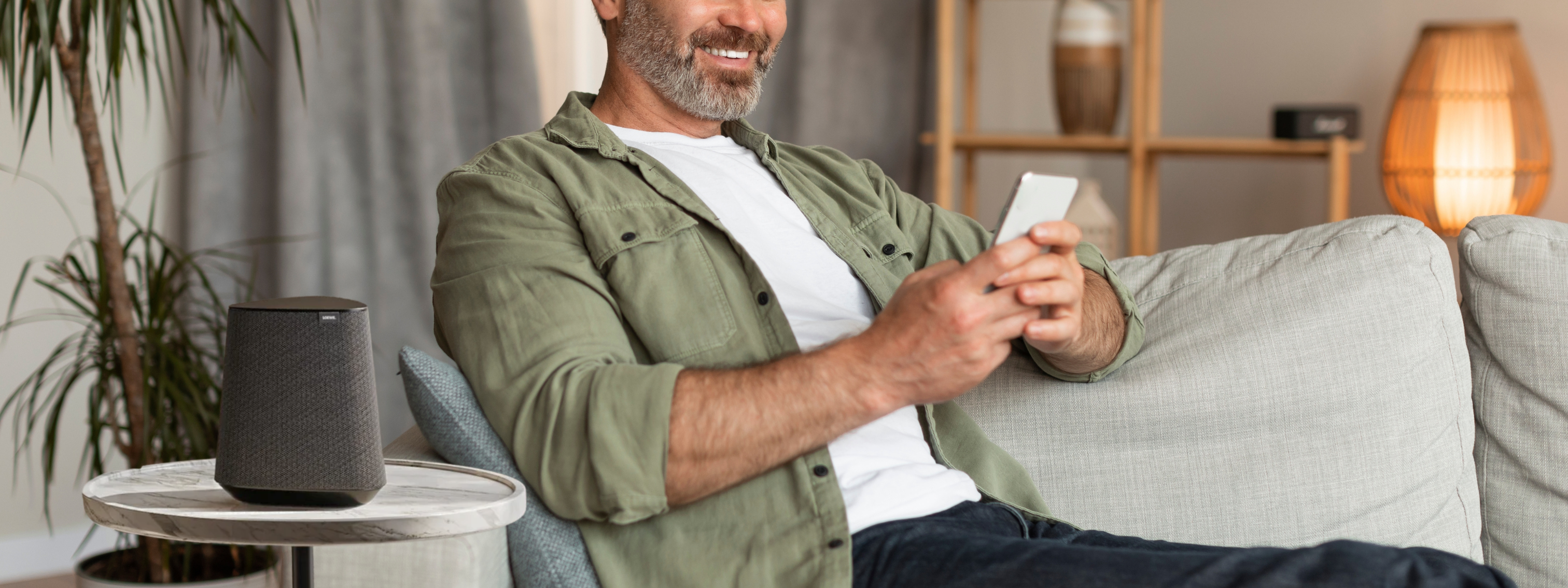 Wide banner featuring MR1 speaker beside a relaxed father on a couch in a modern living room – perfect Father’s Day 2025 gift for music lovers